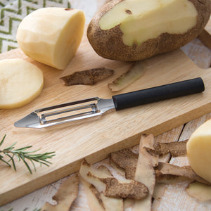 Rada Cutlery Vegetable Peeler with black handle on cutting board with potatoes.